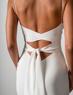 the back of a woman wearing a white dress with an open cutout on it