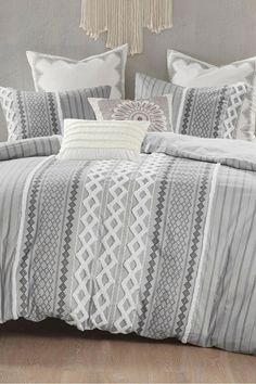 a bed with grey and white striped comforter set on top of a wooden floor