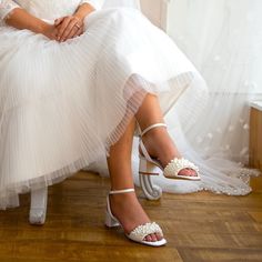 a woman in white shoes sitting on a chair with her legs crossed and wearing high heels