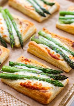 asparagus and cheese puff pastry on a baking sheet with some cut in half