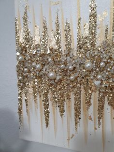 a painting with gold glitter and pearls on it's sides, hanging on a wall