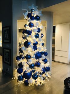 a blue and white christmas tree with snowflakes on it's top, in a living room