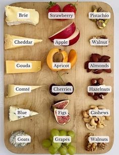 a wooden cutting board topped with lots of different types of cheeses and fruit on top of it