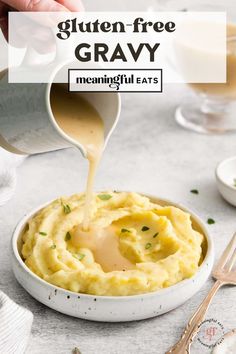 a person pouring gravy over mashed potatoes in a white bowl