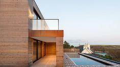 an outdoor swimming pool next to a building with wooden slats on the sides and glass doors