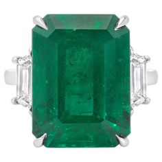 An elegant engagement ring, showcasing a C. Dunaigre certified 12.82 carats emerald cut green emerald, set on a classic four prong setting. Accented by two trapezoid cut diamonds weighing 1.02 carats total with D-E color and VS+ clarity. Elegantly made with a platinum mounting. Size 6.5, resizable upon request.  Roman Malakov is a custom house, specializing in creating anything you can imagine. If you would like to receive a special quote on a custom piece, please message or call us. Diamonds Direct, Emerald And Diamond Ring, Vintage Cocktail Ring, Colombian Emeralds, Three Stone Engagement, Three Stone Engagement Rings, Diamond Gold, Emerald Jewelry, Platinum Ring