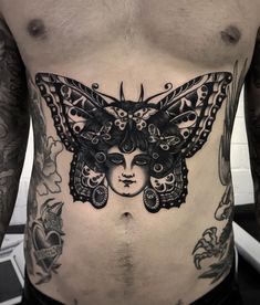 a man's stomach with a butterfly tattoo on his chest and head in the middle