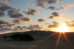 the sun is setting over some sand dunes