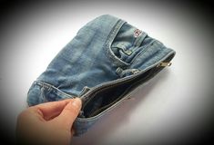 a person is opening the pocket of a pair of jeans with their thumb in it