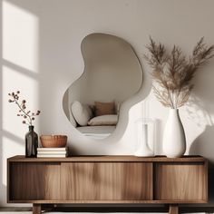 a white vase sitting on top of a wooden dresser next to a mirror and plant