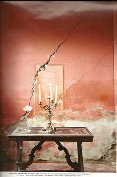 a table with a candle on it in front of a wall that has peeling paint