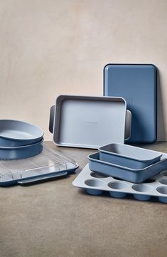 several blue dishes and pans on a table with a beige wall in the background