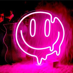 a smiley face neon sign sitting on top of a white furry floor next to a wall