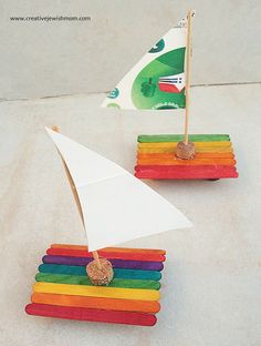 two small boats made out of popsicle sticks with a flag in the back ground