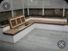 a wooden bench sitting on top of a stone floor next to a brick wall and planters