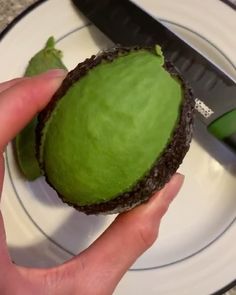 a person is cutting an avocado on a plate