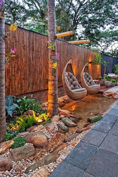 two chairs sitting in the middle of a garden next to a wooden fence and trees