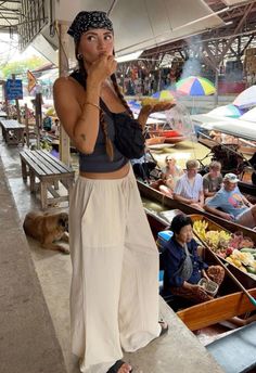 a woman standing under an umbrella in front of other people at a boat dock eating food