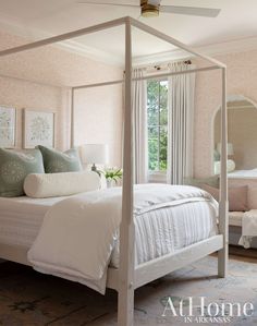 a white bed sitting next to a window in a room with pink walls and furniture