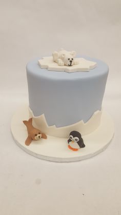 a blue and white cake with two bears on the top, one bear is laying down