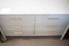 a white dresser with gold handles and drawers