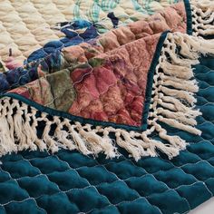 two quilted bedspreads with tassels and fringes on them are laying next to each other