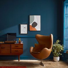 an egg chair sits in front of a blue wall