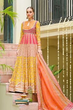 Multicolored Khaadi Silk Pishwas with Jamawar Bodice. Discover Anarkali dresses, Pishwas suits, Pakistani and Bollywood-inspired designs, embroidered frocks, gowns, and traditional attire for a stunning look. Latest trends in ethnic fashion, festive Anarkali outfits, and elegant Pishwas dresses online.Celebrate the vibrant hues of love with this stunning printed khaddi silk pishwas, a kaleidoscope of contrasting shades including Orange, Red, Pink, Peach, and Yellow. The self jamawar bodice, delicately laced with gota work, adds an element of richness to this bridal ensemble. Ideal for a daytime mehndi look, this outfit promises to be a vision of radiance and joy.The full-sleeved pishwas, adorned with a keyhole neckline, captures the essence of Anarkali dresses, embodying the grace and char Mayoon Bride, Pakistani Mehndi Dress, Pakistani Bridal Lehenga, Wedding Dresses Pakistani, Bridal Mehndi Dresses, Pakistani Bridal Dress, Mehndi Dress, Salwar Dress, Gota Work