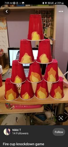 a bunch of red cups sitting on top of a wooden table next to a computer