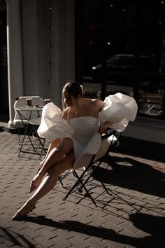 a woman is sitting in a chair on the street with her legs spread wide open