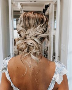 a woman with blonde hair in a white dress is looking at herself in the mirror