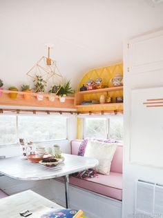 a kitchen table and chairs in front of a window with potted plants on the windowsill