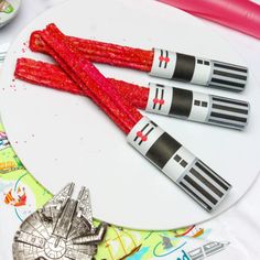 three star wars rockets on a white plate with red glitters next to other toys