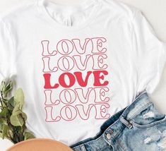 a t - shirt with the words love, love and love on it next to some denim shorts