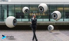 a woman is talking on her cell phone in front of an art installation that looks like eyeballs