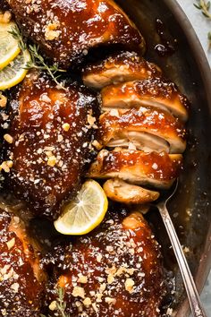 a pan filled with chicken covered in sauce and garnished with sliced lemons