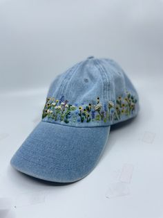 a light blue hat with embroidered flowers on the front and side, sitting on a white surface