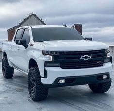 a white truck parked on top of a parking lot next to a building with a sky background