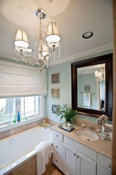 a bath room with a tub a sink and a large mirror on the wall next to a window