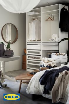 a bedroom with clothes on hangers and a table in the corner next to it