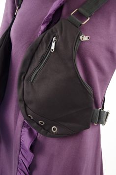 a woman wearing a purple shirt and black purse with zippers on the front pocket