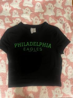 a black shirt that says philadelphia eagles on the front and green letters on the back