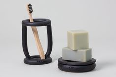 a toothbrush holder and soap dish made out of black rubber, with two blocks of soap stacked on top of each other