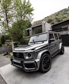 a silver mercedes g class parked in front of a house