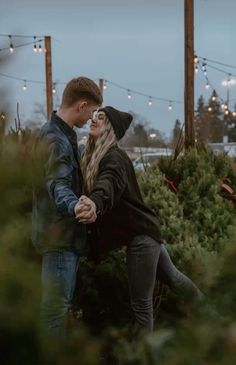 a man and woman holding hands in front of christmas trees