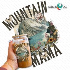 a hand holding a mason jar with the words mountain mama on it and an image of mountains in the background