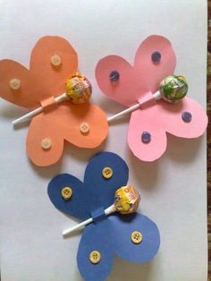 three flower shaped lollipops on top of a piece of paper with buttons