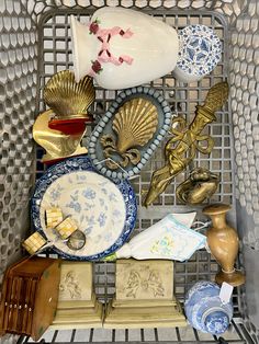 a metal basket filled with lots of different types of plates and vases next to each other