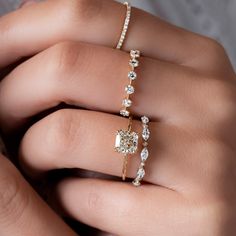 a woman's hand with two rings on her fingers and the ring has three diamonds in it