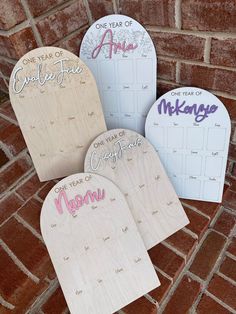 three wooden calendars with the names of each month on them sitting next to a brick wall